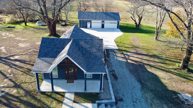 view of front of home featuring covered porch, a garage, an outdoor structure, and a front yard