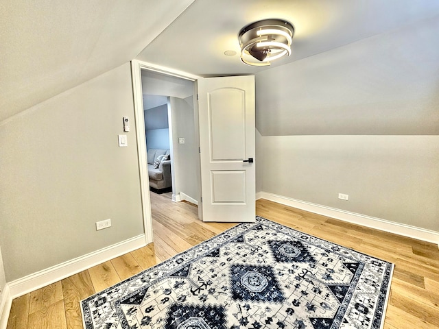 additional living space with light wood-type flooring and lofted ceiling