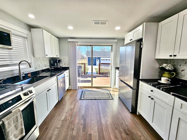 kitchen featuring appliances with stainless steel finishes, backsplash, dark hardwood / wood-style floors, and white cabinetry