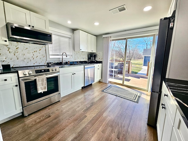 kitchen with white cabinets, decorative backsplash, stainless steel appliances, and dark wood-type flooring