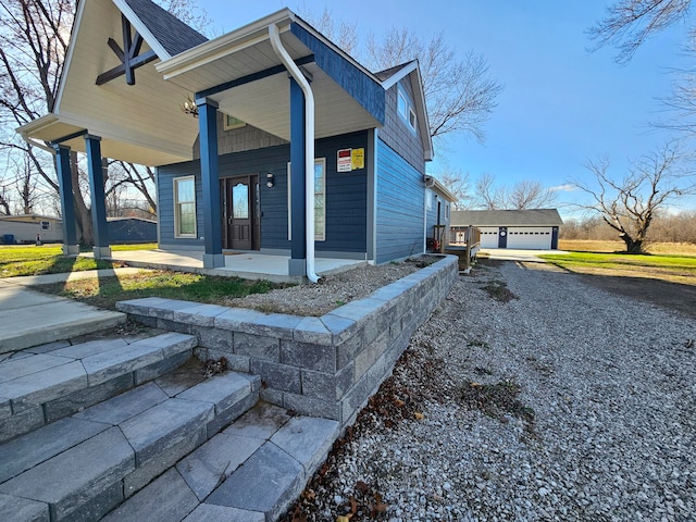 view of side of property with a garage, covered porch, and an outbuilding