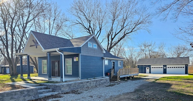 view of front facade with a wooden deck, an outbuilding, and a garage