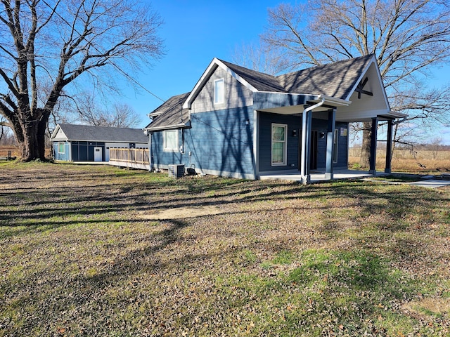 view of front of home featuring central AC, an outdoor structure, and a front lawn