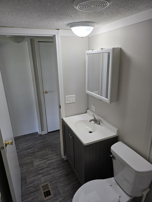 bathroom with vanity, wood-type flooring, a textured ceiling, and toilet