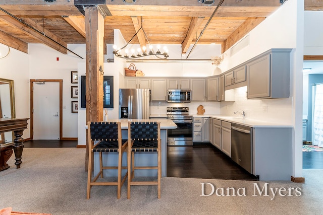 kitchen featuring dark hardwood / wood-style flooring, wood ceiling, stainless steel appliances, pendant lighting, and beamed ceiling