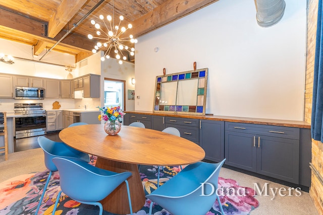 dining area with beam ceiling, light carpet, a chandelier, and a high ceiling