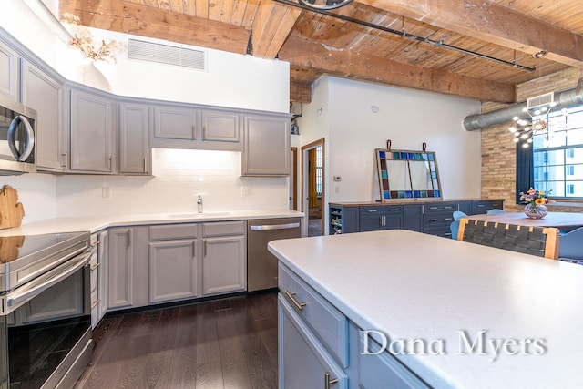 kitchen with pendant lighting, wooden ceiling, appliances with stainless steel finishes, beam ceiling, and dark hardwood / wood-style flooring