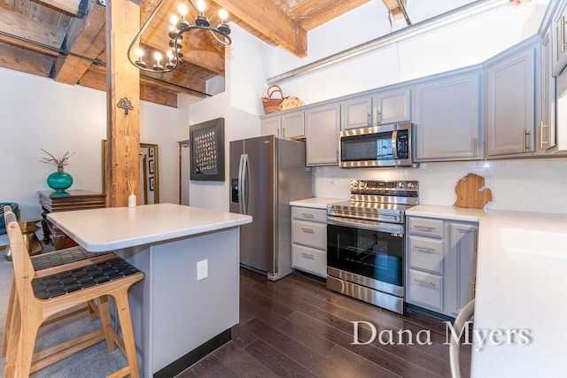 kitchen with appliances with stainless steel finishes, tasteful backsplash, pendant lighting, dark hardwood / wood-style floors, and a breakfast bar area