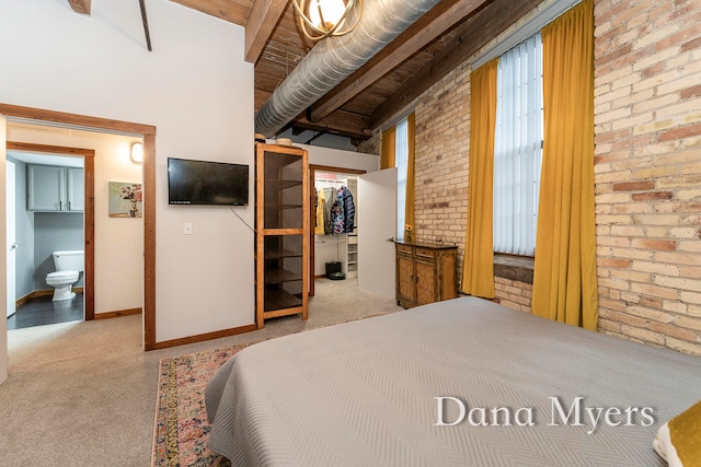 carpeted bedroom featuring a walk in closet, ensuite bathroom, brick wall, lofted ceiling with beams, and a closet