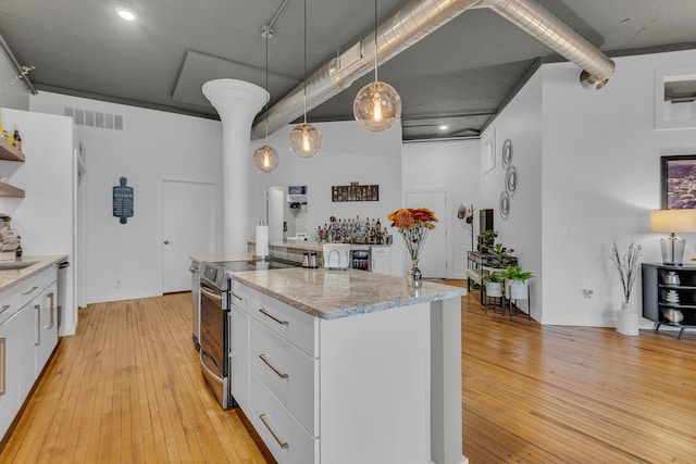 kitchen featuring appliances with stainless steel finishes, light hardwood / wood-style floors, white cabinetry, and pendant lighting