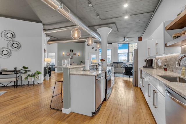 kitchen with appliances with stainless steel finishes, ceiling fan, sink, light hardwood / wood-style flooring, and white cabinetry