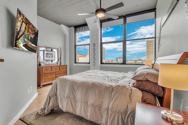 bedroom featuring ceiling fan, light hardwood / wood-style floors, and multiple windows