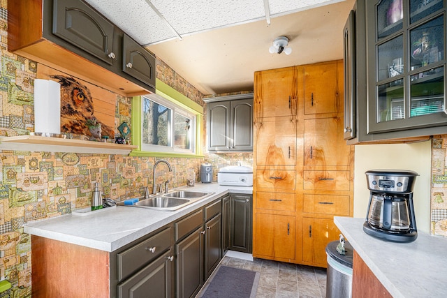 kitchen with a paneled ceiling, decorative backsplash, dark brown cabinets, and sink