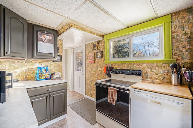 kitchen featuring a paneled ceiling, white appliances, and light tile patterned floors