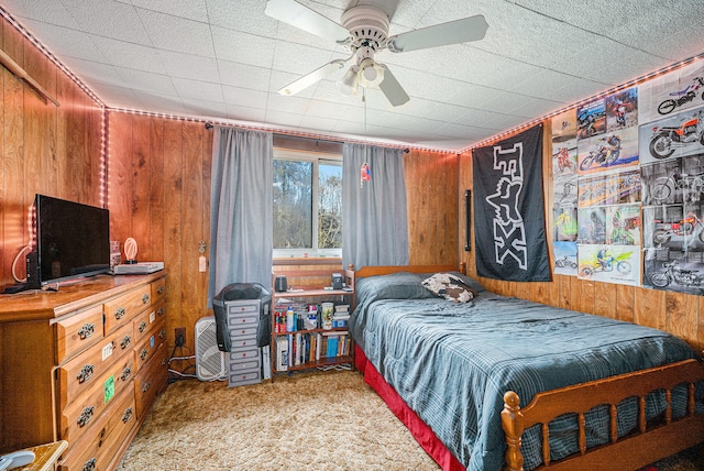 carpeted bedroom with ceiling fan and wooden walls