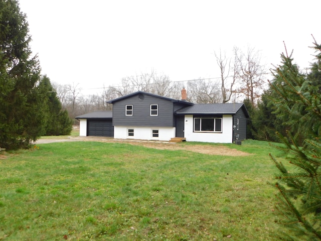 back of property with a garage and a yard