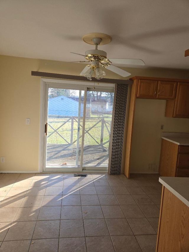 unfurnished dining area with ceiling fan and light tile patterned flooring