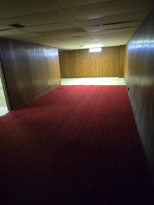 basement with wood walls and a drop ceiling