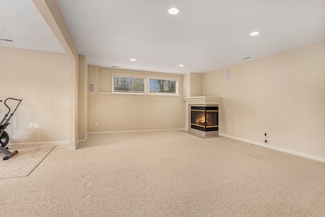 basement with a multi sided fireplace and light colored carpet