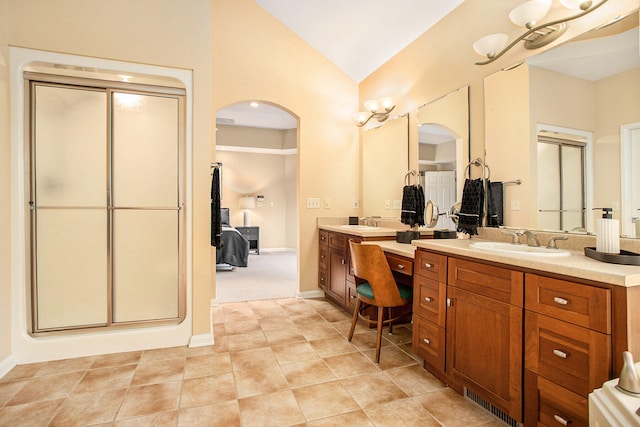 bathroom featuring vanity, a shower with shower door, and vaulted ceiling