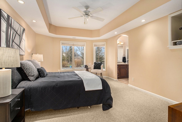 carpeted bedroom with ceiling fan, connected bathroom, and a tray ceiling