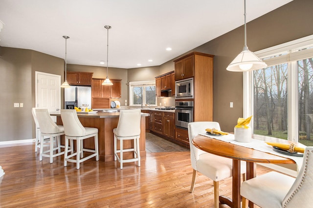 kitchen featuring a center island, stainless steel appliances, decorative light fixtures, and wood-type flooring