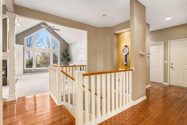 hallway with hardwood / wood-style flooring, decorative columns, and vaulted ceiling