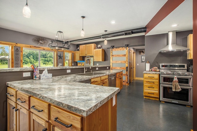 kitchen featuring pendant lighting, wall chimney range hood, sink, a kitchen island, and stainless steel appliances