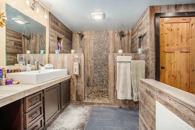 bathroom with wooden walls, vanity, and walk in shower