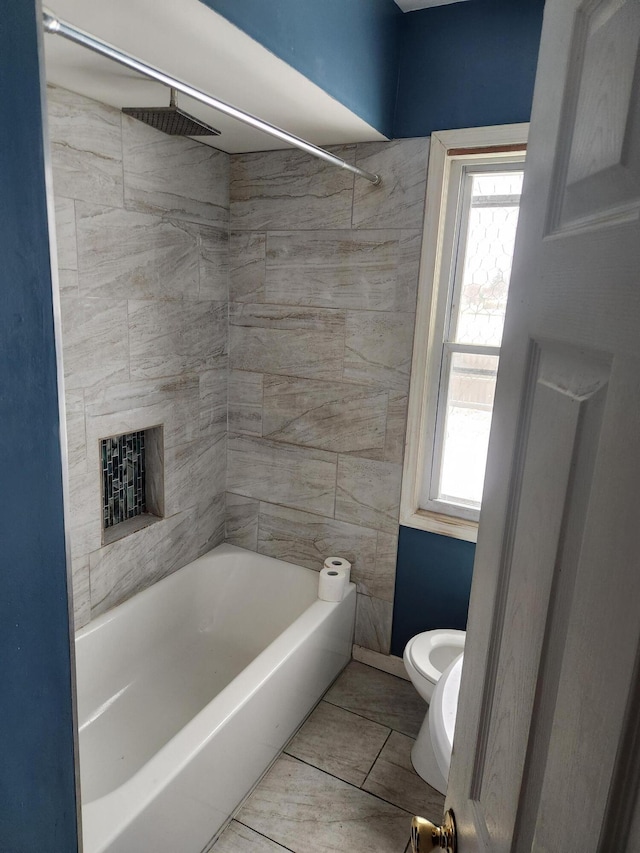 bathroom with toilet and tiled shower / bath