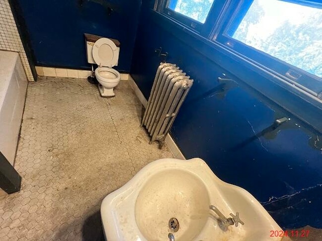 bathroom with toilet, radiator heating unit, and a bath