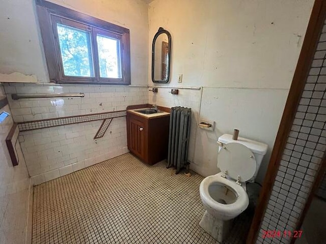 bathroom with radiator, vanity, tile walls, tile patterned flooring, and toilet