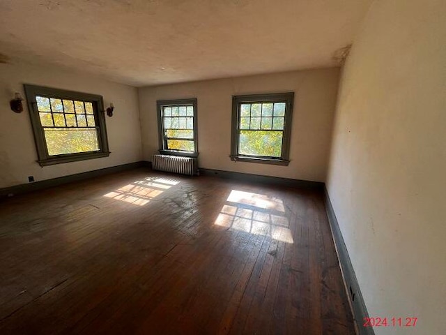 unfurnished room with radiator heating unit and dark wood-type flooring