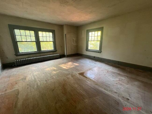 spare room with radiator heating unit and wood-type flooring