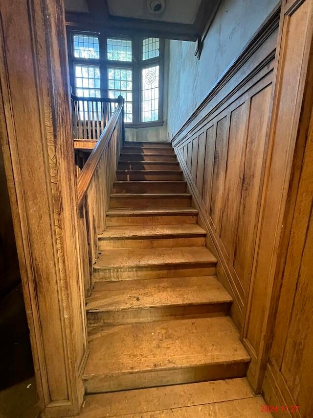 stairway featuring hardwood / wood-style flooring and wooden walls