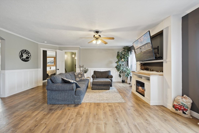 living room featuring a textured ceiling, ceiling fan, crown molding, and light hardwood / wood-style flooring