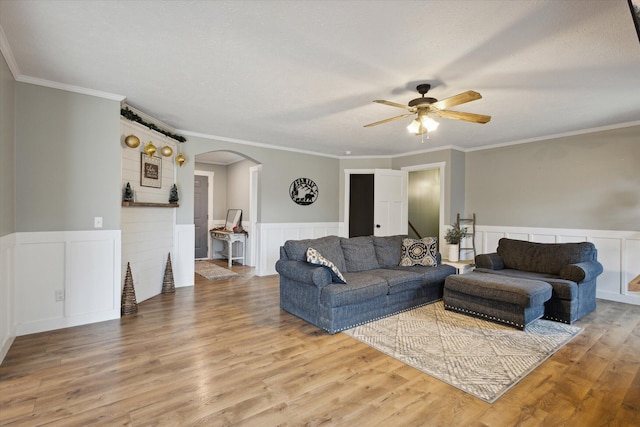 living room featuring ceiling fan, ornamental molding, a textured ceiling, and hardwood / wood-style flooring