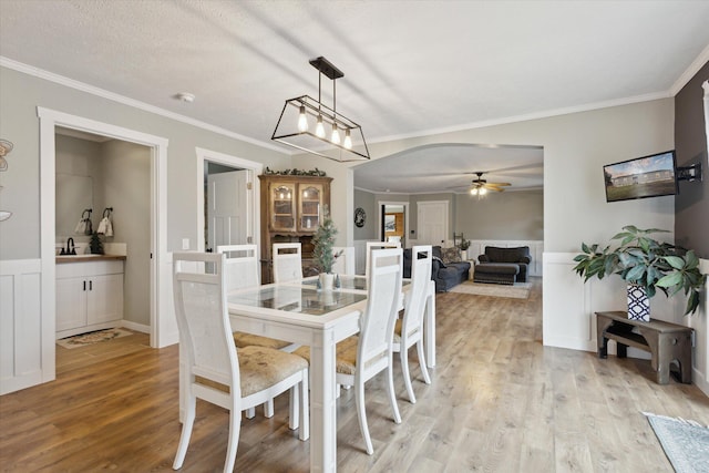 dining space featuring ceiling fan, ornamental molding, and light hardwood / wood-style flooring