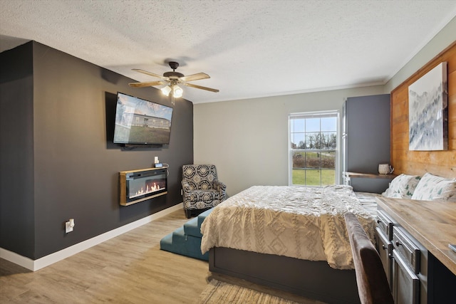 bedroom with a textured ceiling, light wood-type flooring, and ceiling fan