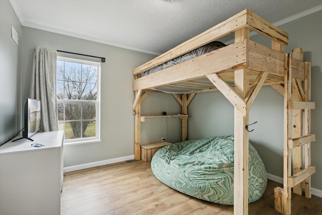 bedroom featuring a textured ceiling, wood-type flooring, and ornamental molding