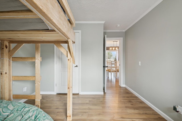 bedroom featuring crown molding, hardwood / wood-style floors, and a textured ceiling