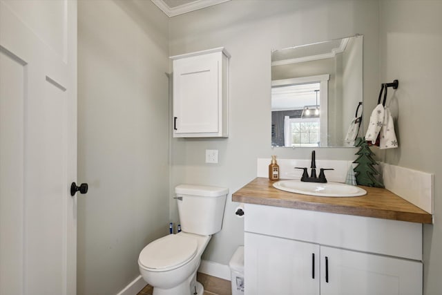 bathroom with toilet, vanity, and ornamental molding