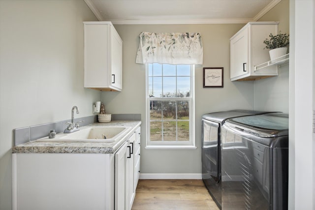 laundry area with sink, cabinets, light hardwood / wood-style flooring, crown molding, and washer and dryer