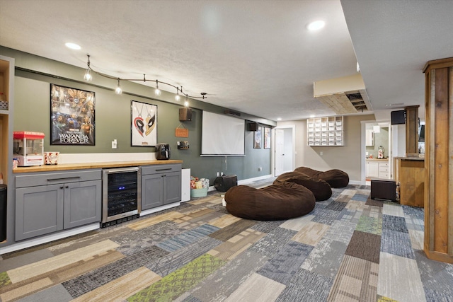 interior space with wine cooler, gray cabinets, a textured ceiling, and wood counters