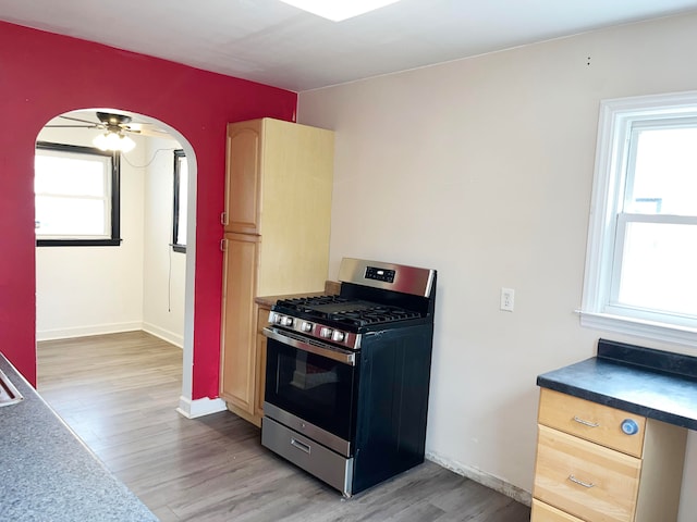 kitchen featuring dark countertops, gas range, light brown cabinets, and wood finished floors