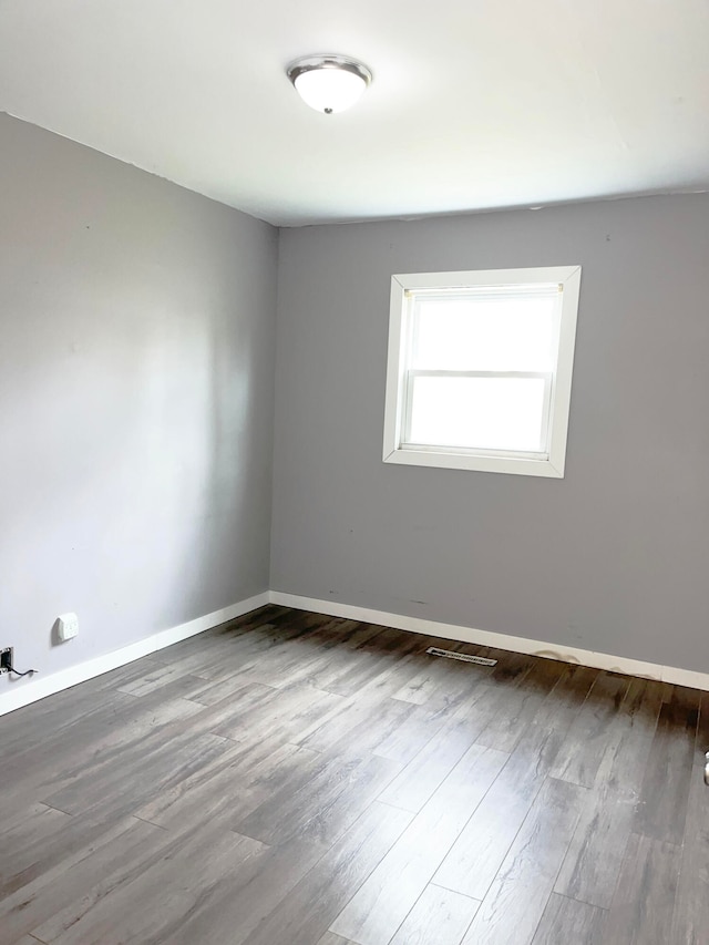 spare room with visible vents, baseboards, and wood finished floors