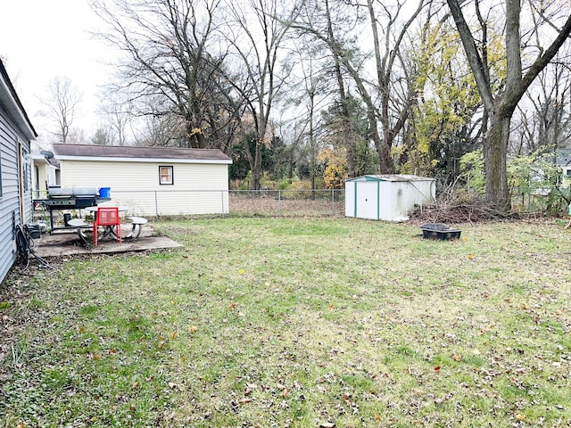 view of yard with a fire pit, a storage unit, an outdoor structure, and a fenced backyard