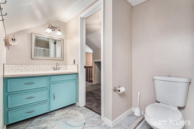 bathroom featuring vanity, lofted ceiling, and toilet