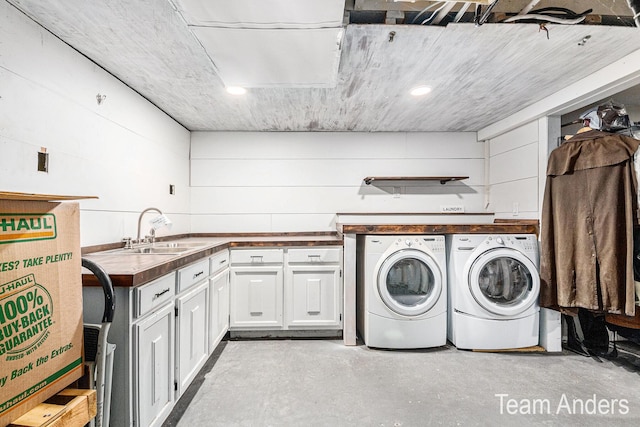 clothes washing area featuring cabinets, washing machine and dryer, and sink