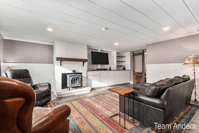 living room with built in shelves, hardwood / wood-style flooring, a wood stove, and crown molding